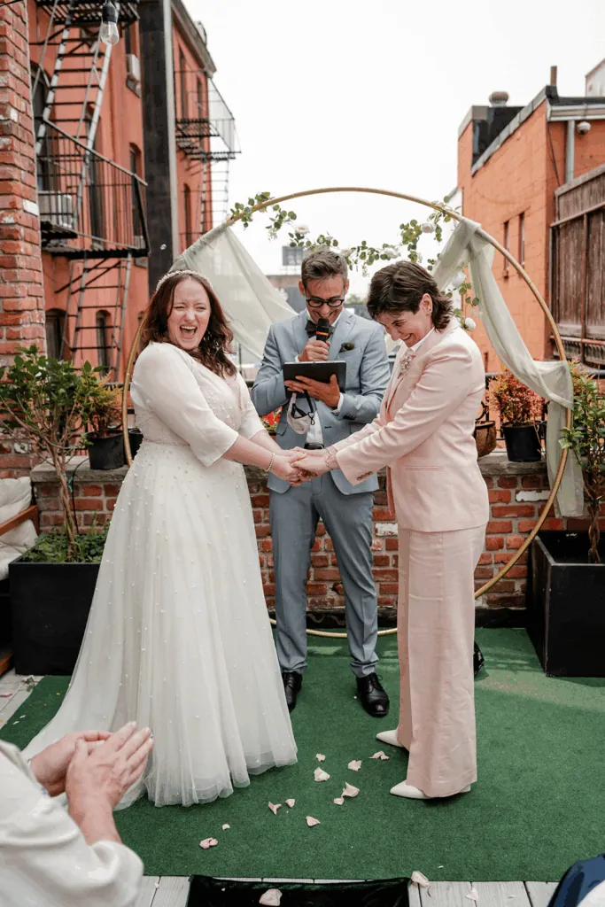Couple exchanging vows under a floral arch with an officiant