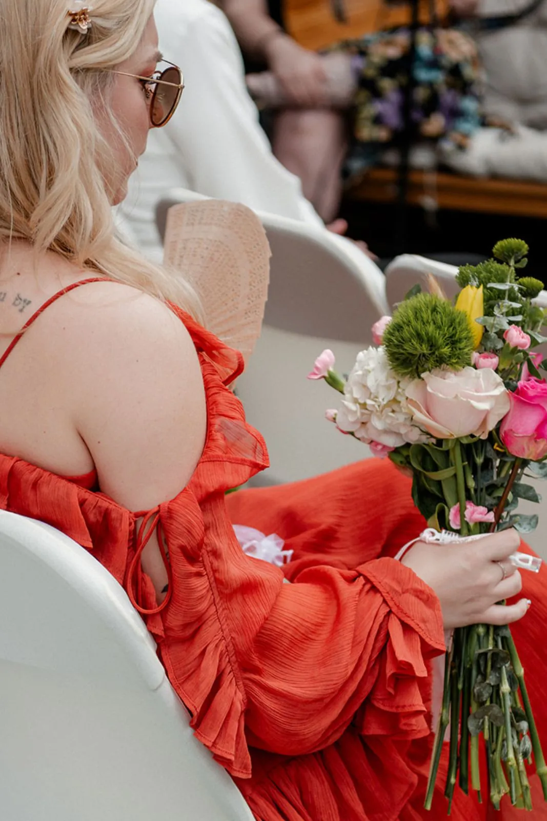 Guest in an orange dress holding a bouquet