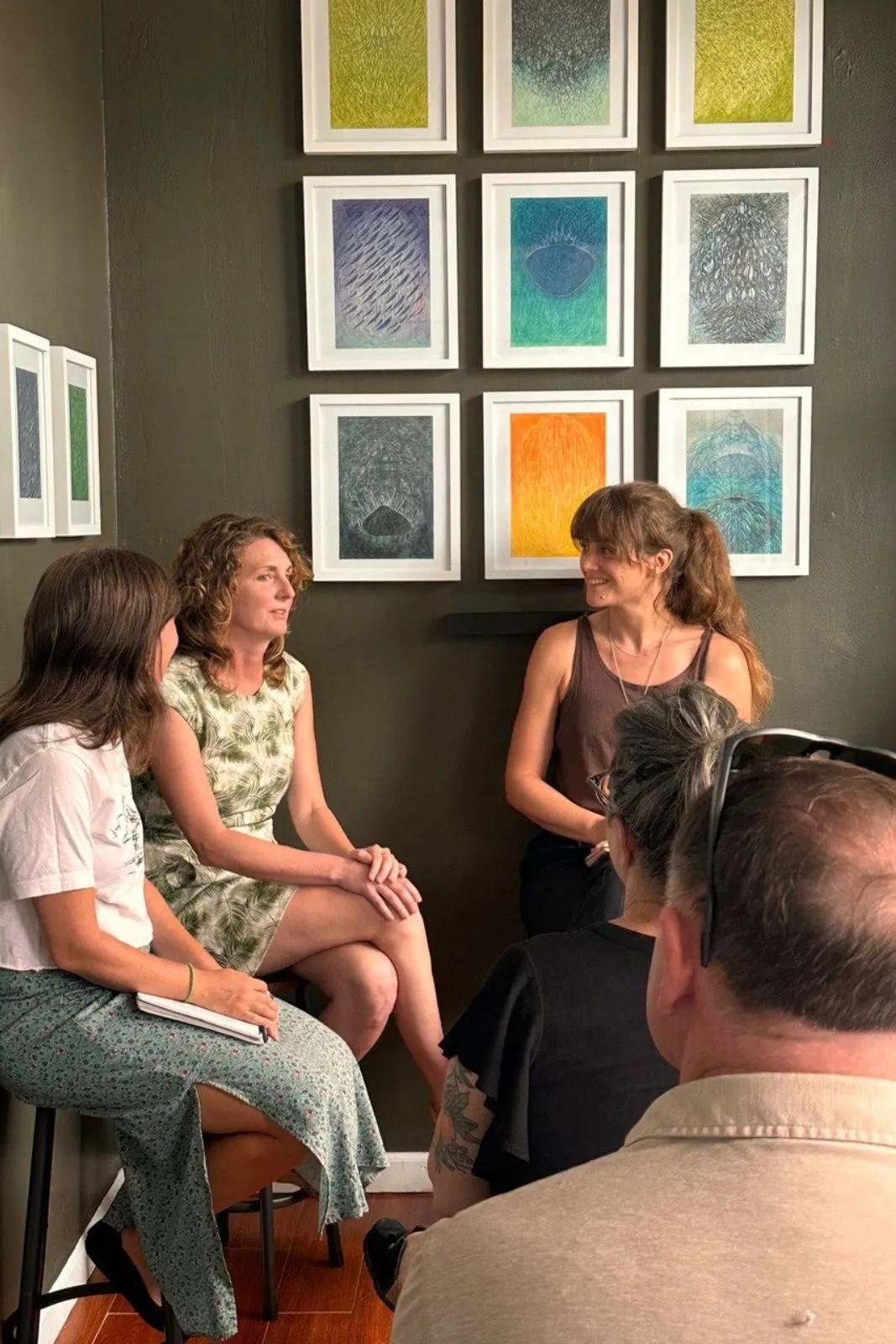 Guests seated in a circle in front of a gallery wall