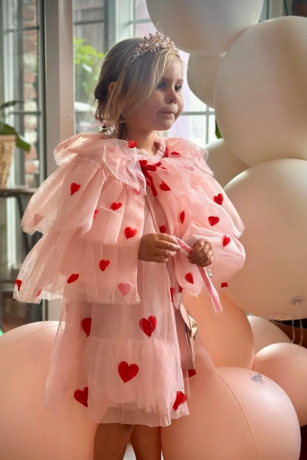 Girl in a pink heart-print tulle dress with balloons